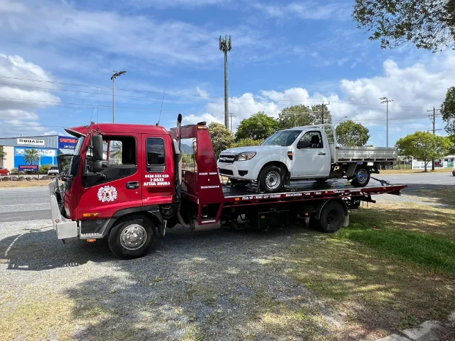 White ute being towed on a red tilt-tray truck in Cairns