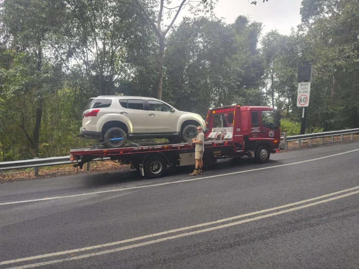 White 4WD being recovered on a winding tropical road near Mossman