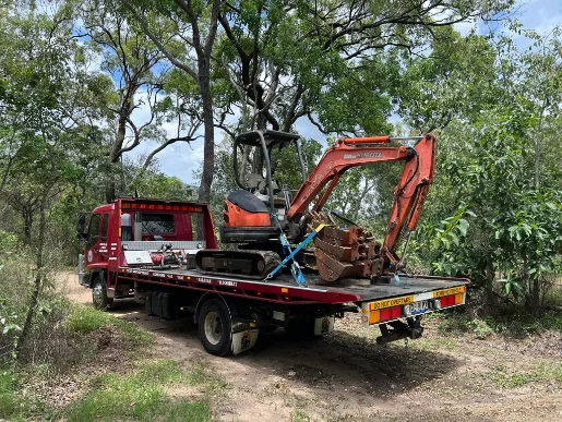 Mini excavator on red tow truck on rural bush track
