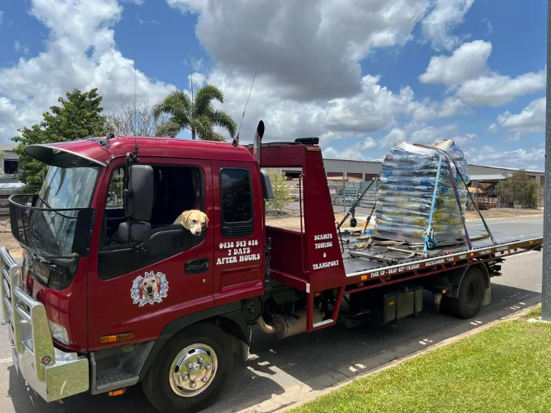 Red tow truck carrying pallets of freight, Cairns