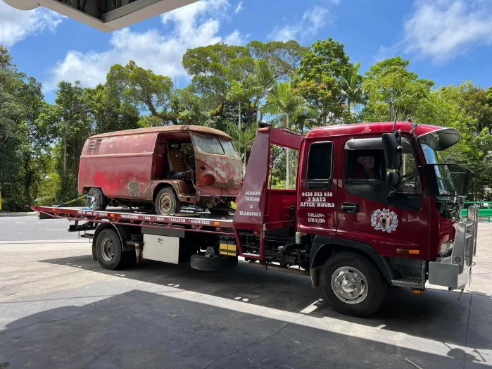 Old VW van loaded on red tilt-tray tow truck