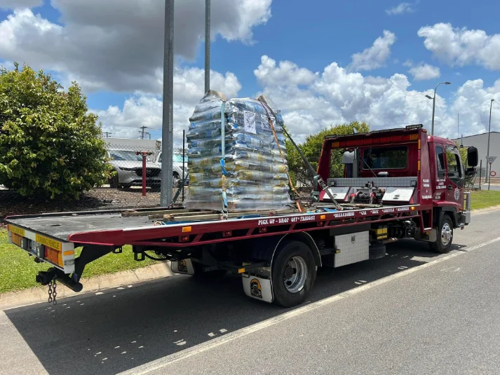 Red tow truck loaded with pallets, wide landscape shot